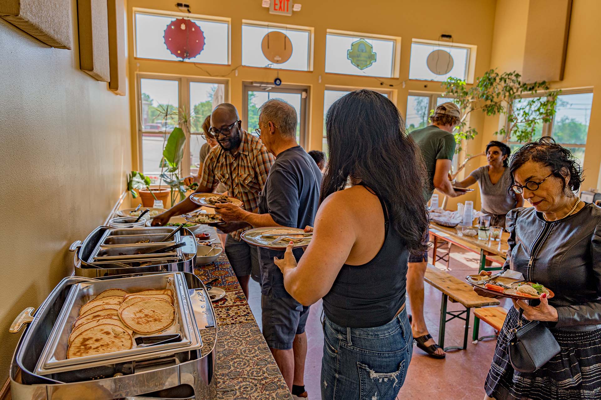 A group of people are standing around a table with food.