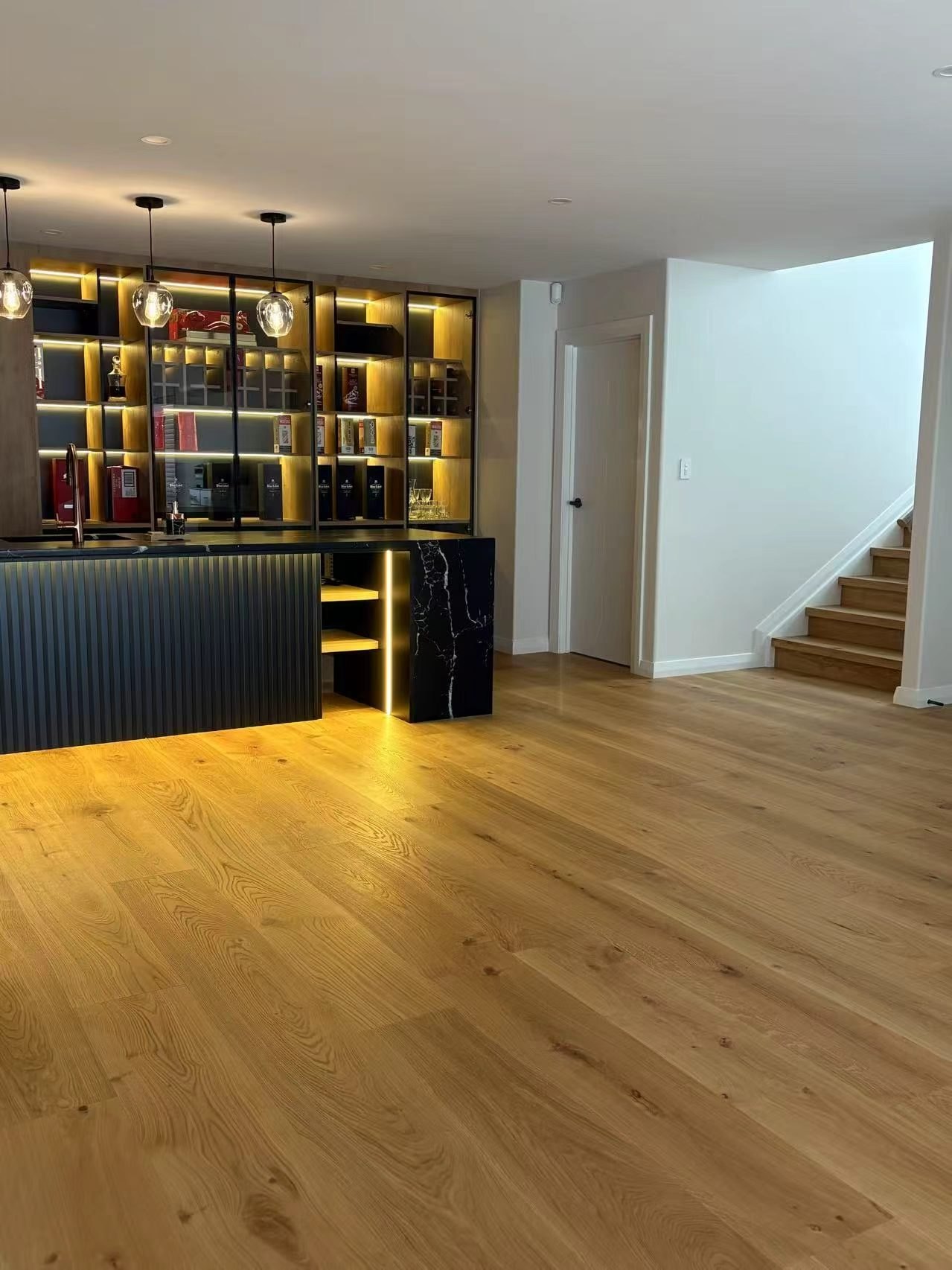 Wide plank oak timber flooring running through a bar and entry to the stairs, laid by Floorical in Tauranga