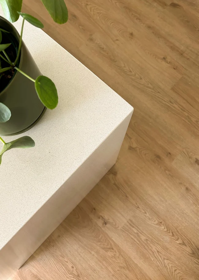 Close detail of mid oak hybrid SPC plank beside a concrete plinth