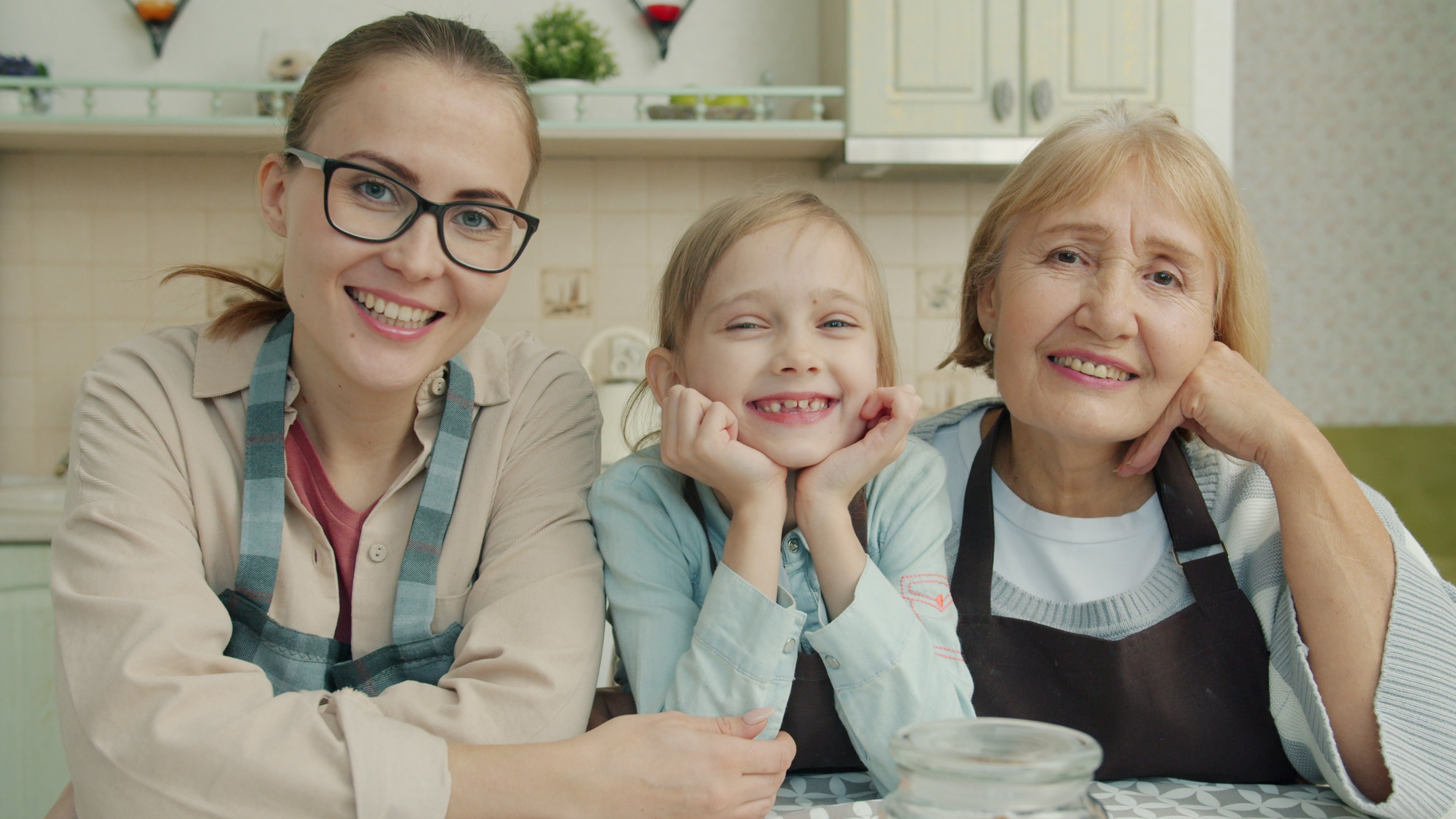 Three generations of a family smiling together in a kitchen