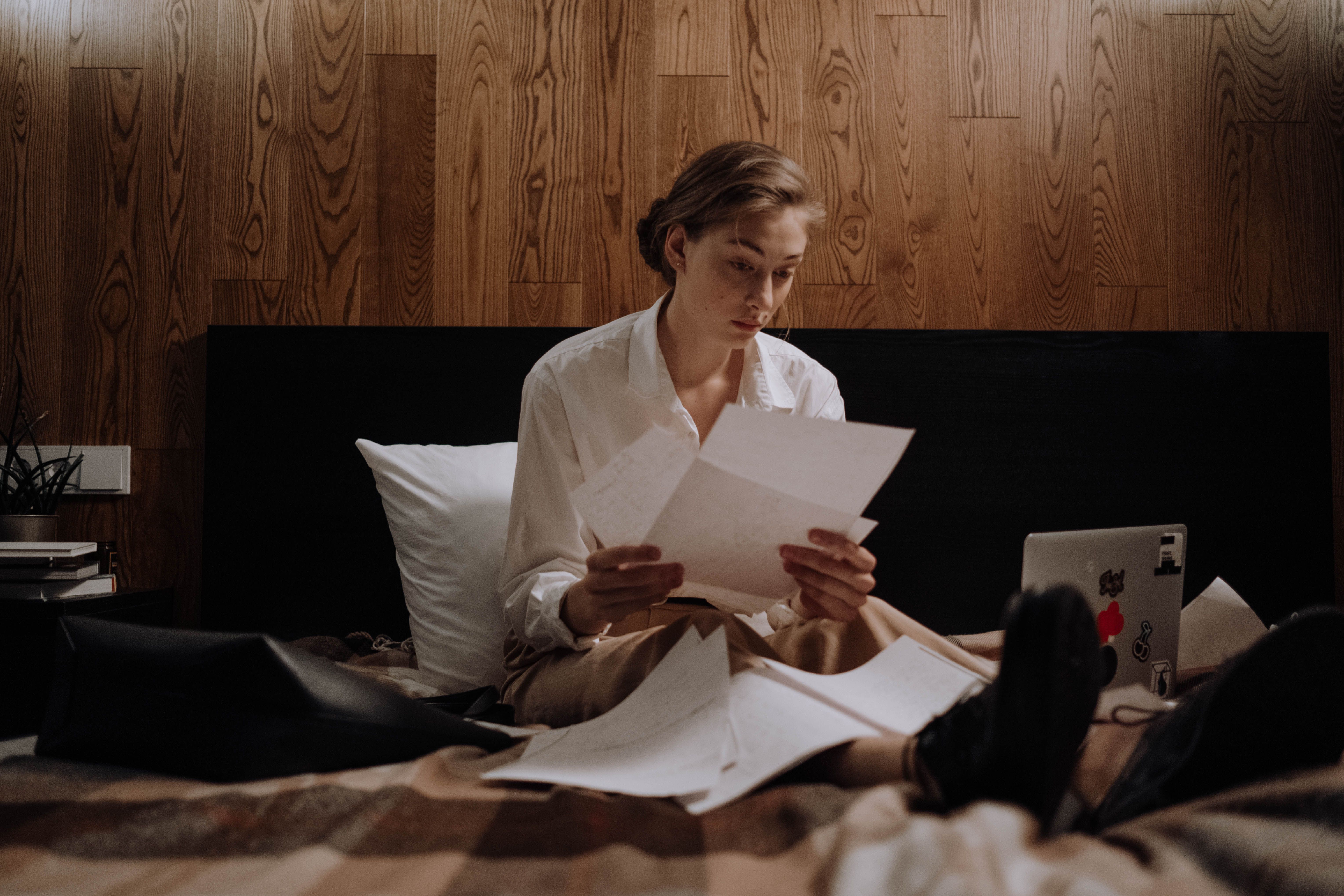 Woman working on paperwork while sitting in bed
