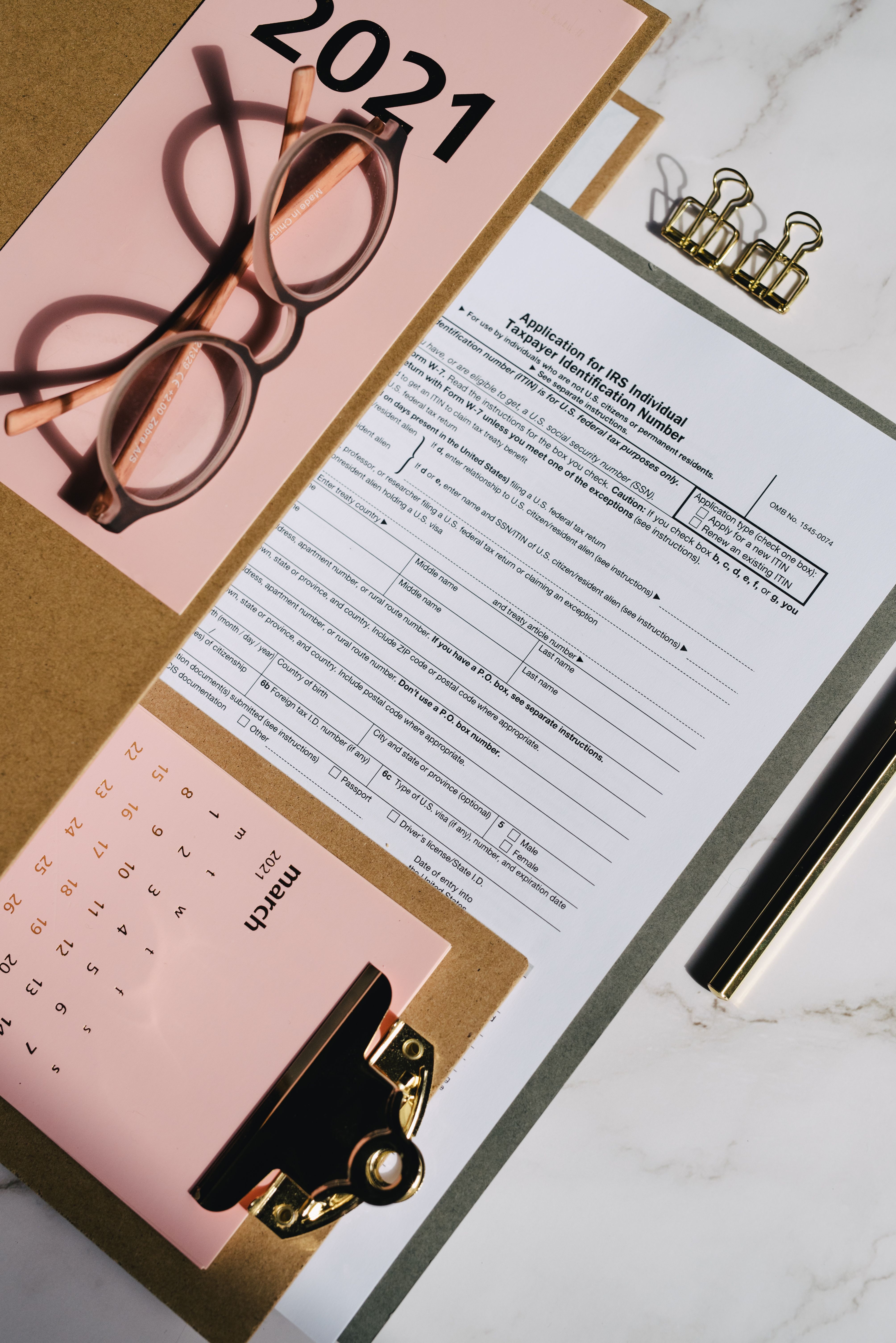 Blank tax forms near a monthly calendar on a clipboard