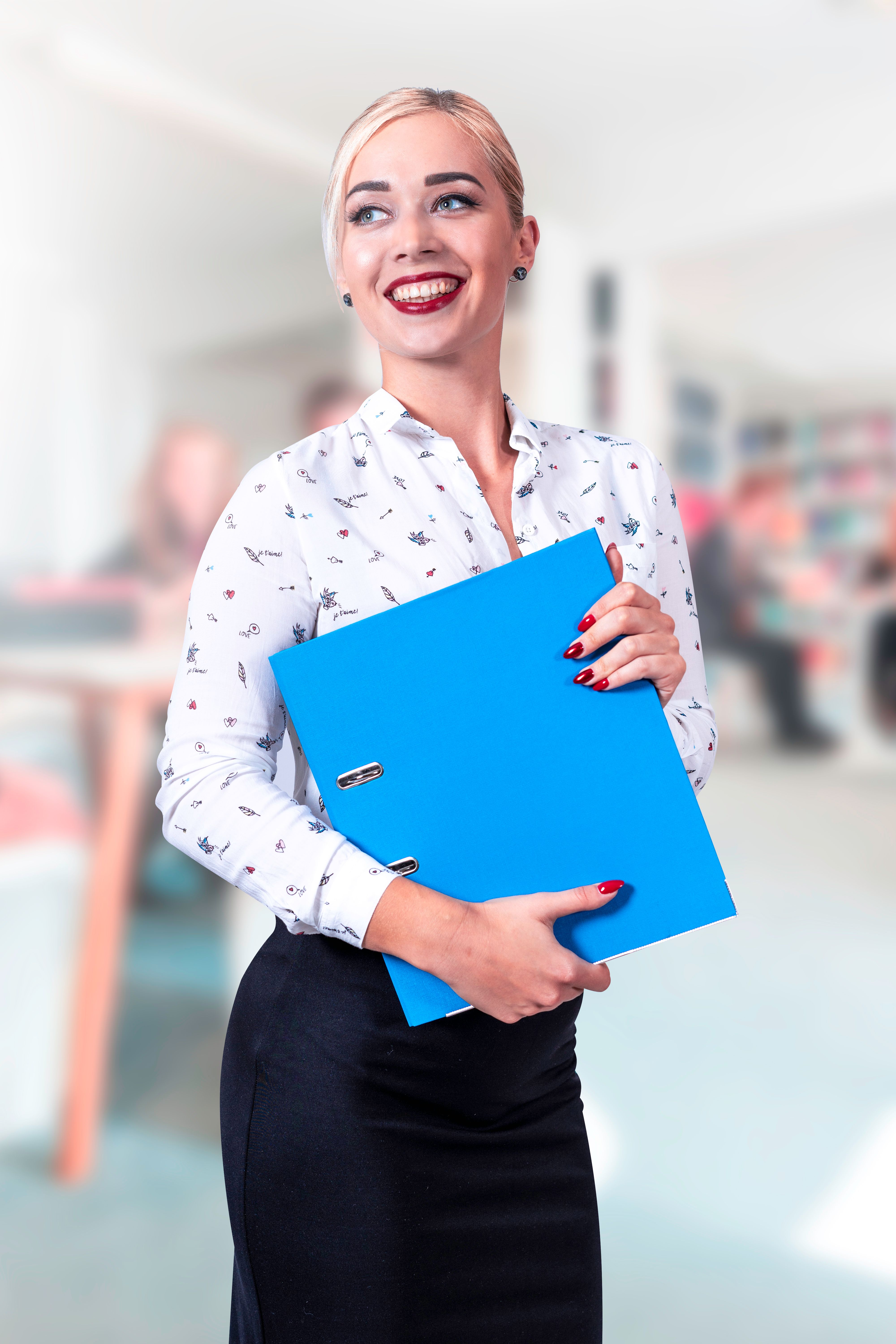 Smiling woman holding a binder in an office