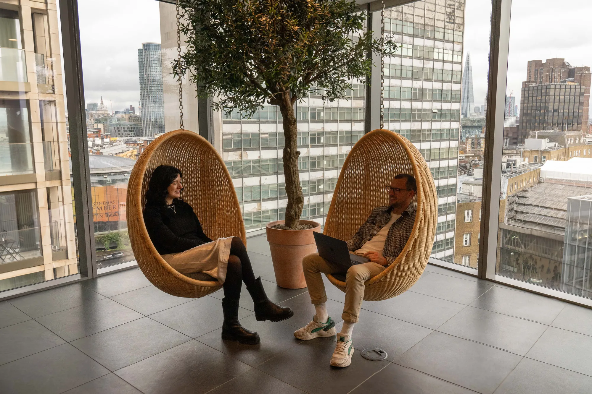 Two of the INCEPTION team chatting in the hanging chairs above Waterloo, with the Shard behind