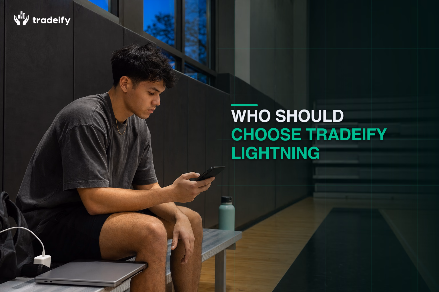 Experienced young futures trader reviewing a phone beside a closed laptop at a municipal recreation center