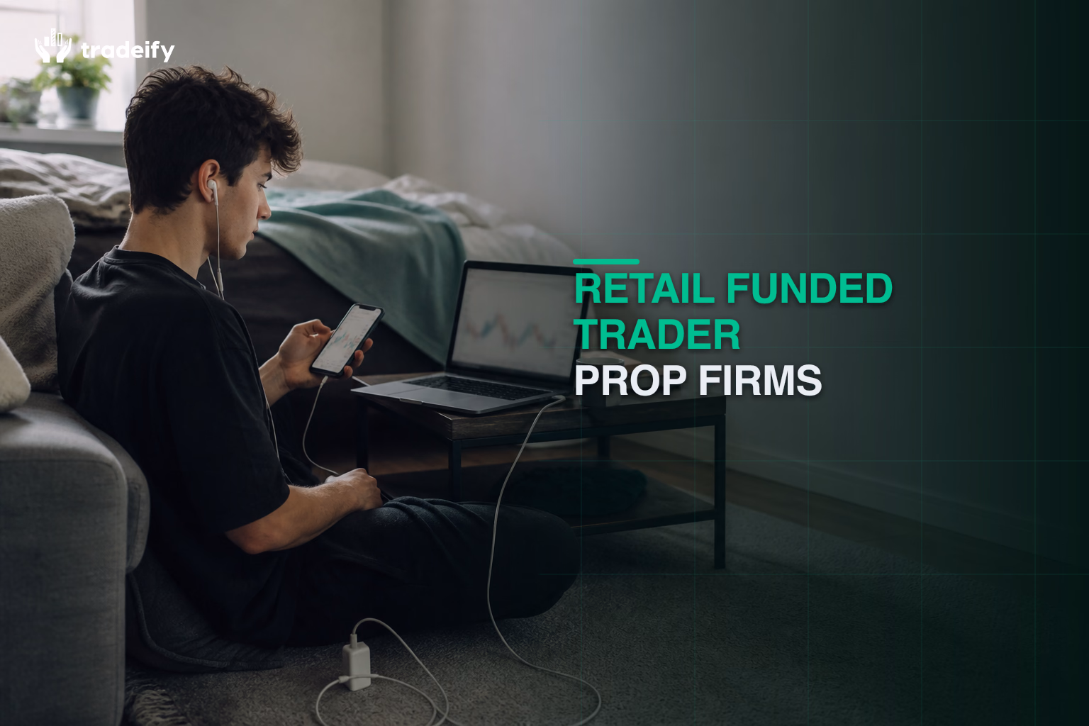 Retail funded trader using a laptop and phone from a lived-in bedroom floor setup