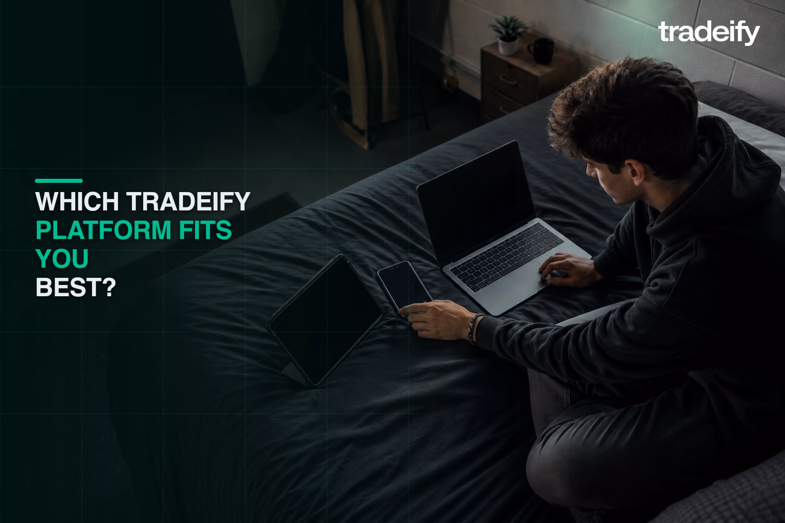 Young trader comparing blank laptop, phone, and tablet screens in a modest dorm room