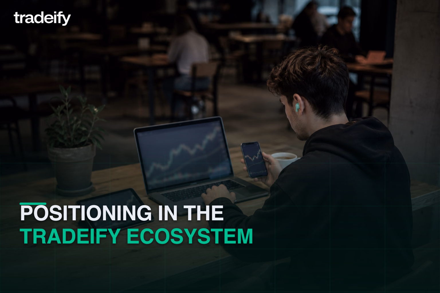 Young trader coordinating softly defocused market context across laptop tablet and phone at a casual coffee shop table
