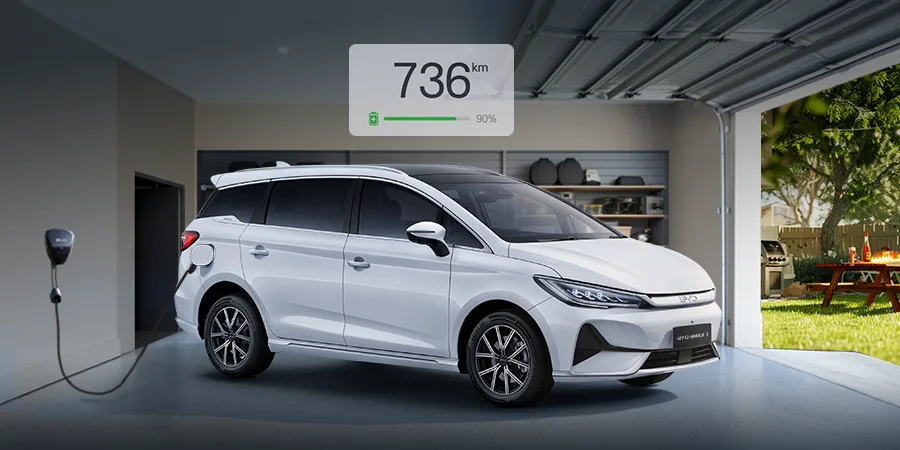 BYD eMAX 7 charging inside a home garage with 736km range display, highlighting long-range EV convenience and smart home charging
