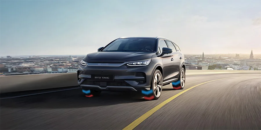 BYD Tang SUV driving on an open road with dual-motor all-wheel drive visualized, showcasing performance and traction technology