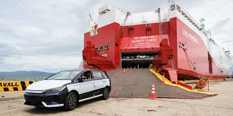 BYD electric vehicle disembarking from a red LNG-powered BYD roll-on/roll-off (RoRo) vessel at Batangas Port during its maiden international delivery of over 1,500 new energy vehicles to the Philippines.