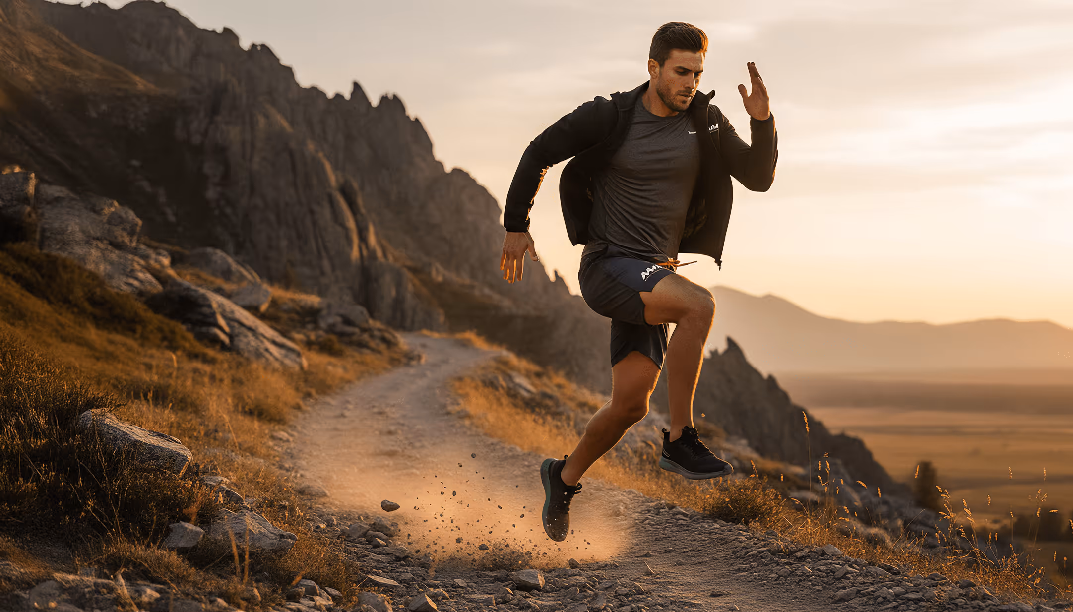 Man running vigorously on a rocky mountain trail at sunset with dust kicking up behind him.
