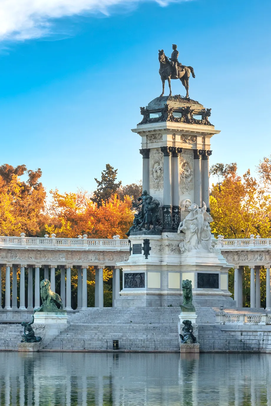 Monumento a Alfonso XII con estatua ecuestre y estanque en un parque con árboles otoñales.