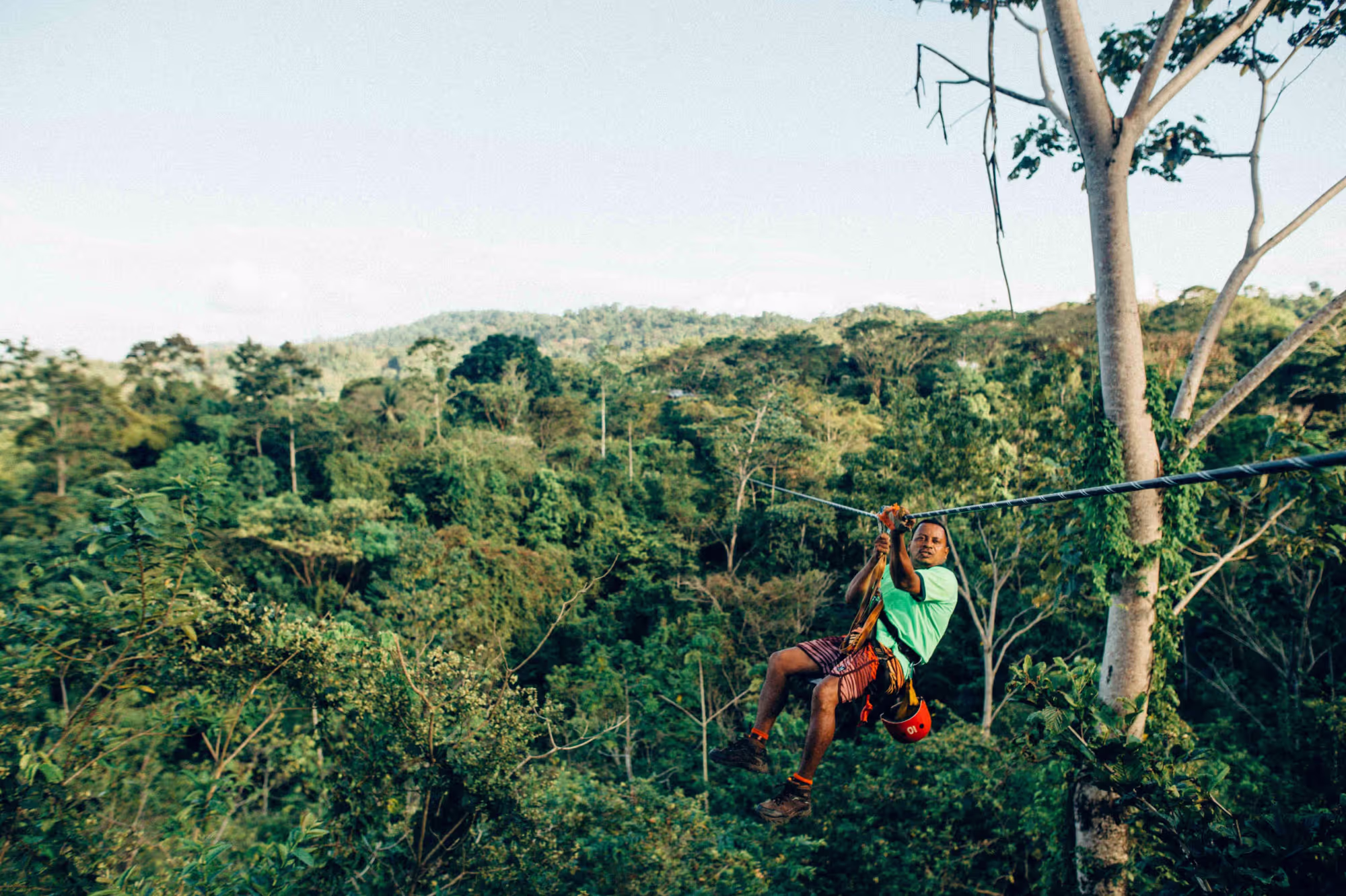 A person ziplining over a lush green forest