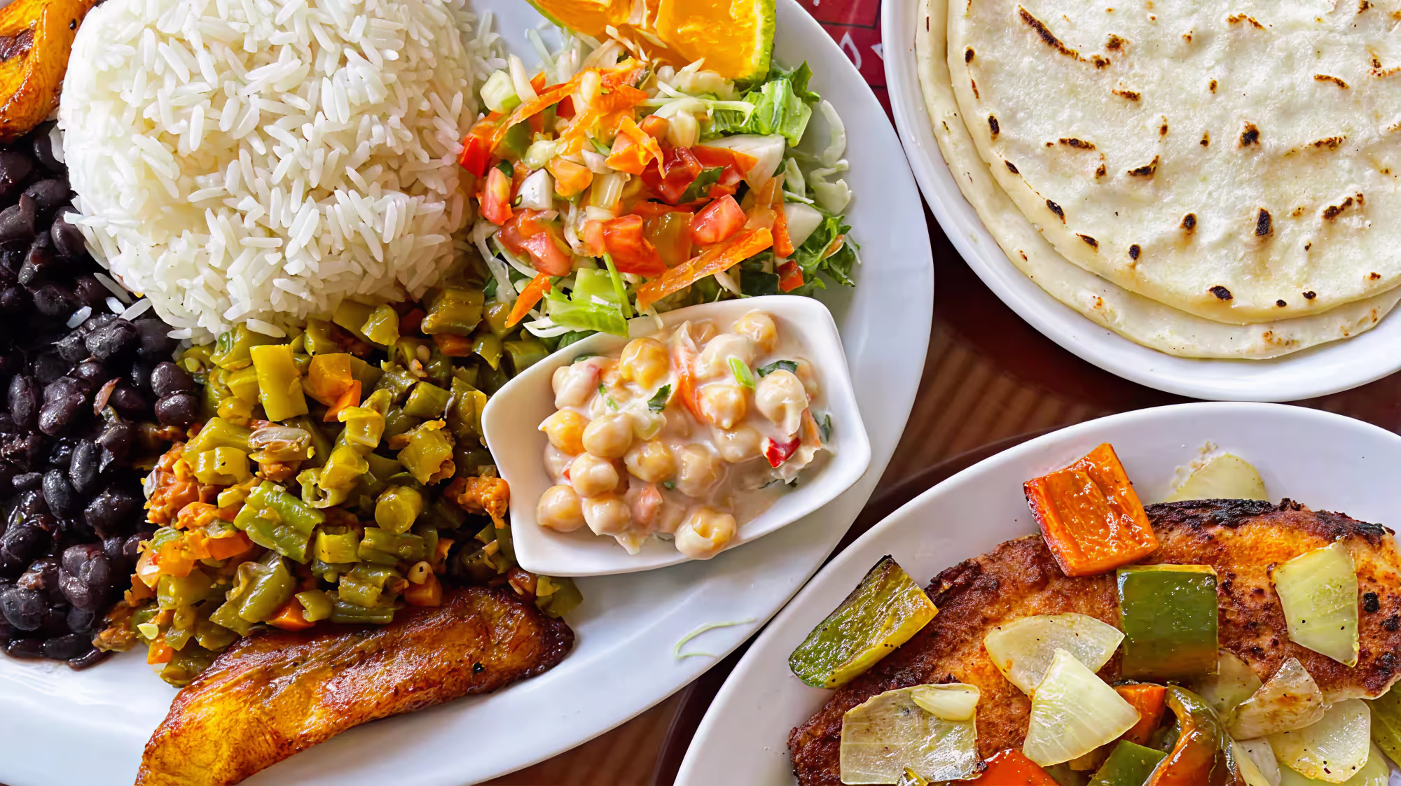 A plate with rice, beans, vegetables, and tortillas