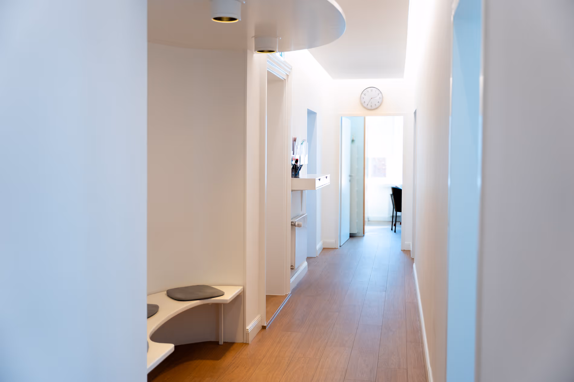 Heller Flur der Praxis Dr. Winter mit Sitzbank und Uhr