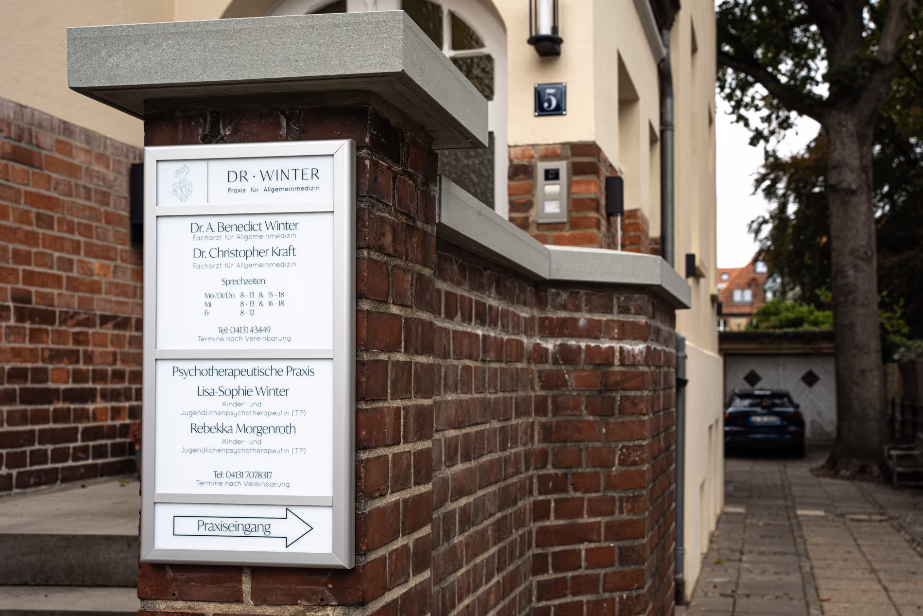 Praxisschild Dr. Winter an Backsteinwand mit Sprechzeiten und Eingangshinweis