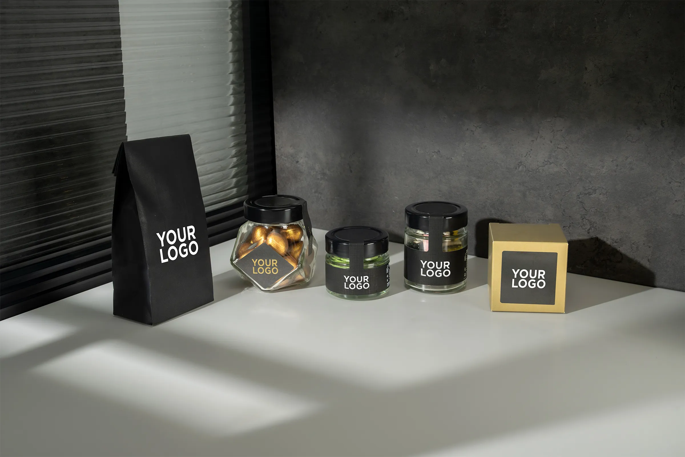 Cinque diverse confezioni delle collezioni per il minibar con scritto "your logo" sopra su sfondo neutro