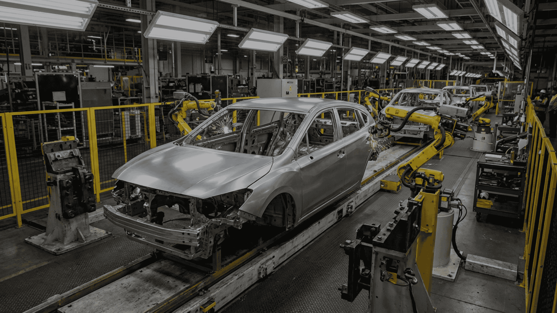 Automotive body shop assembly line with multiple robotic arms welding and assembling a vehicle body-in-white, showcasing high-precision automated manufacturing processes.