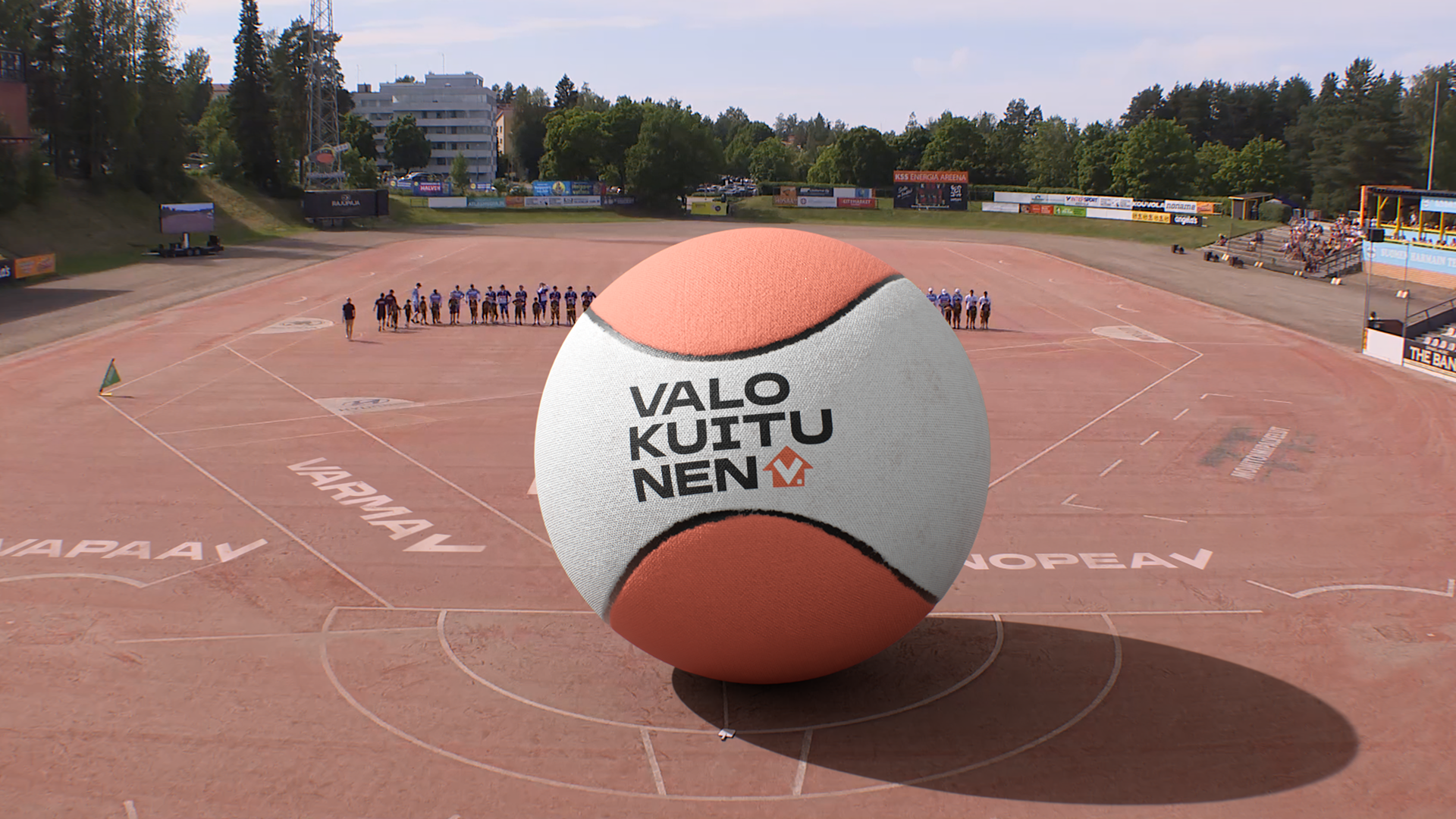 Two men in sportswear sitting on grass at a stadium, each sitting on a soccer ball, with a white tote bag reading 'Varför blir vi har ju buss' in front.