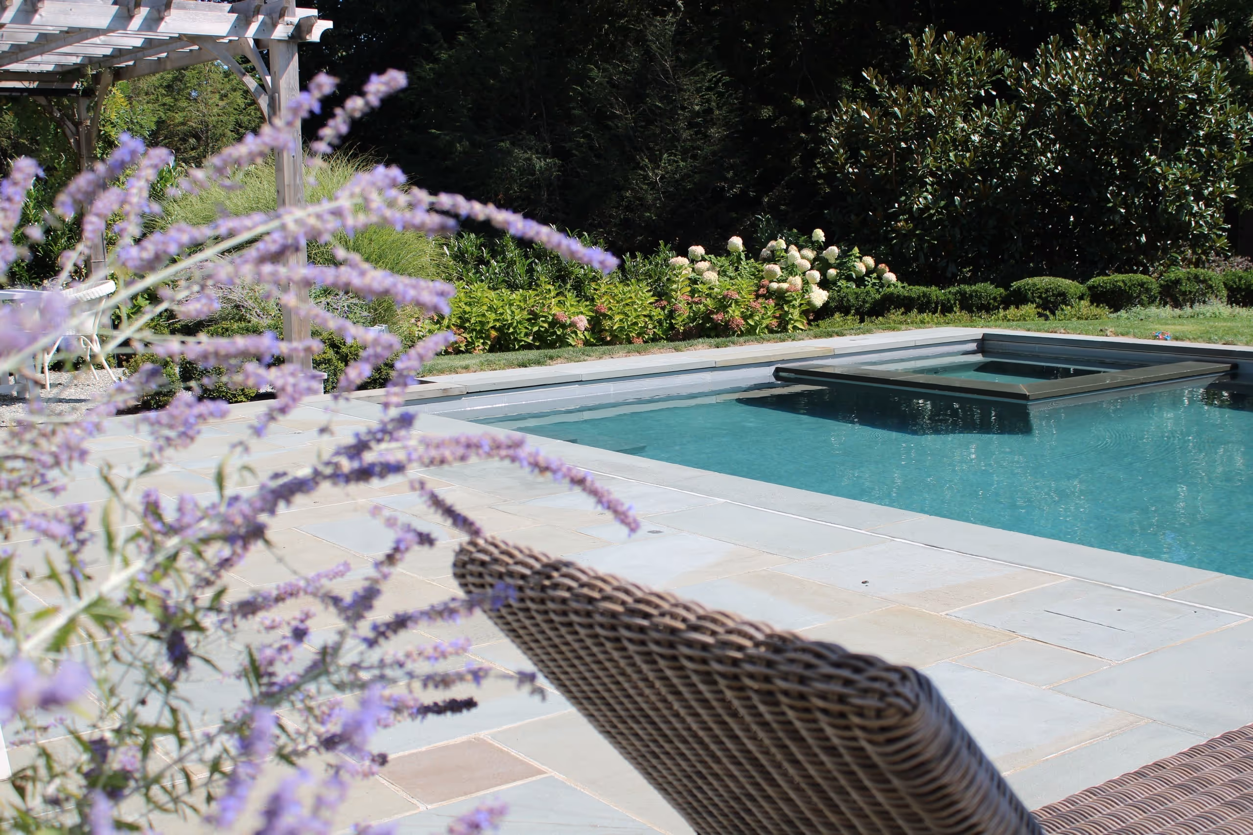 Peaceful backyard pool with garden and seating area in New Canaan, CT by family-run New Canaan Pool Service