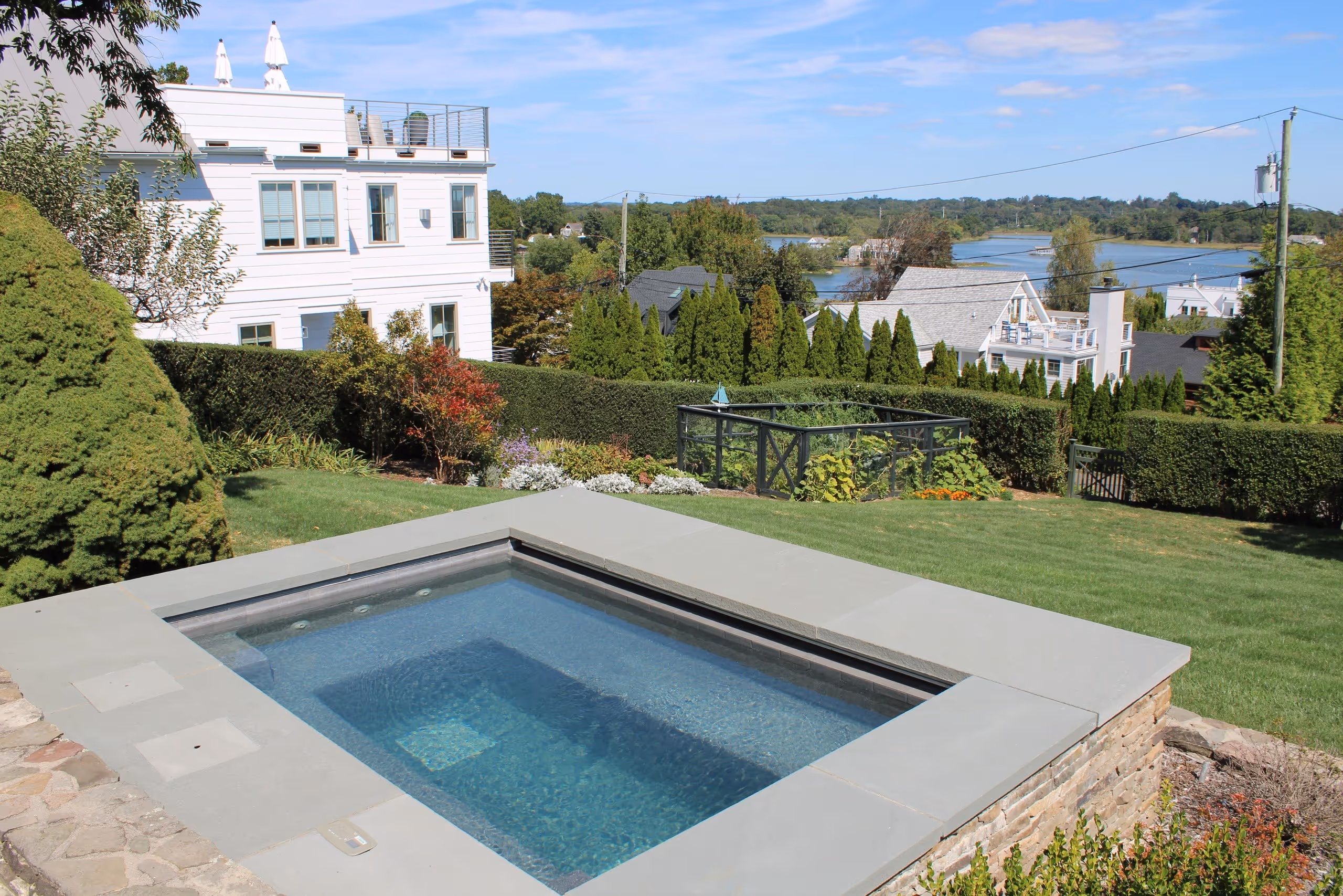 Elevated spa with stone surround and scenic water view in Greenwich, CT by New Canaan Pool Service