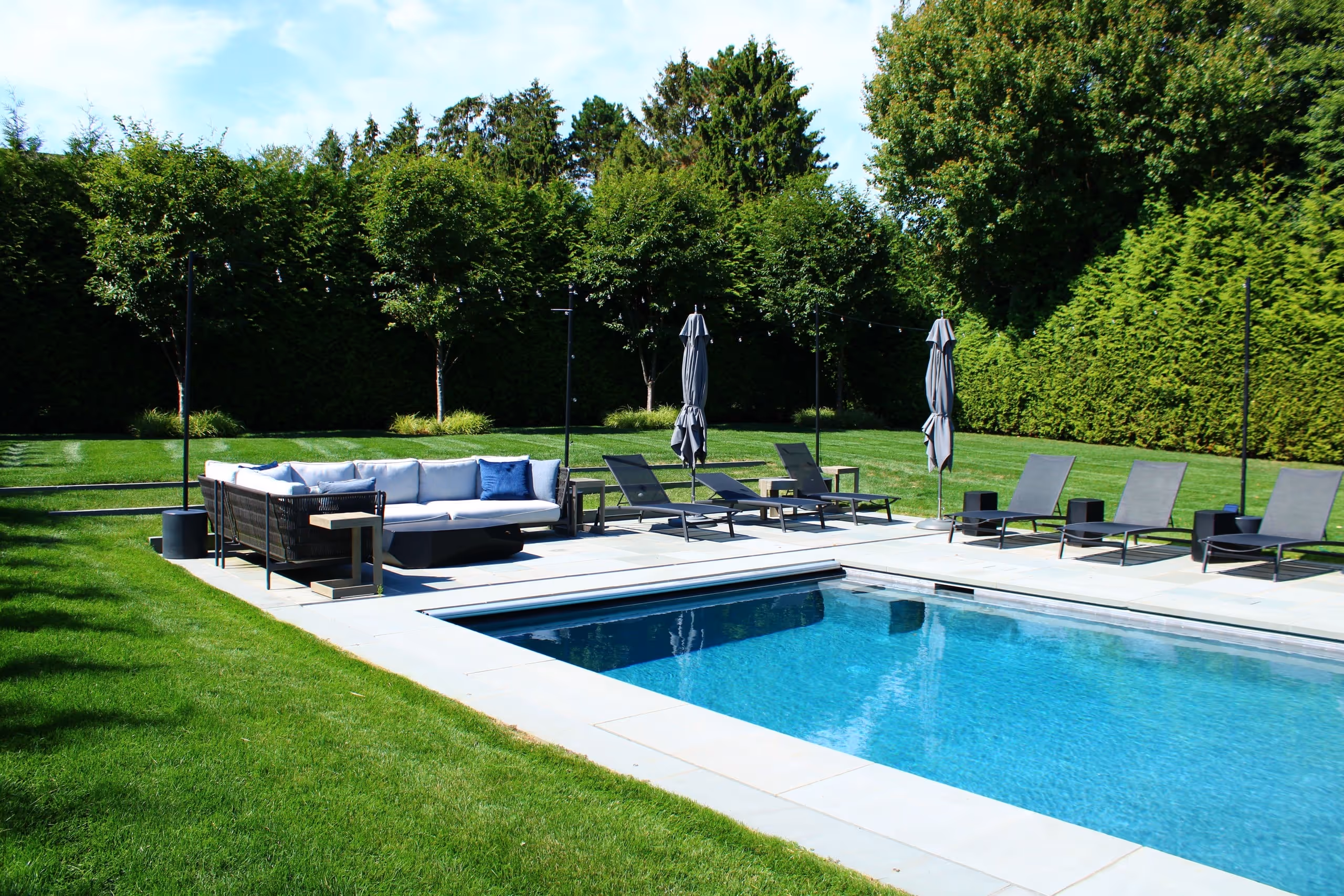 Modern backyard pool with lounge chairs and outdoor seating area in New Canaan, CT by New Canaan Pool Service