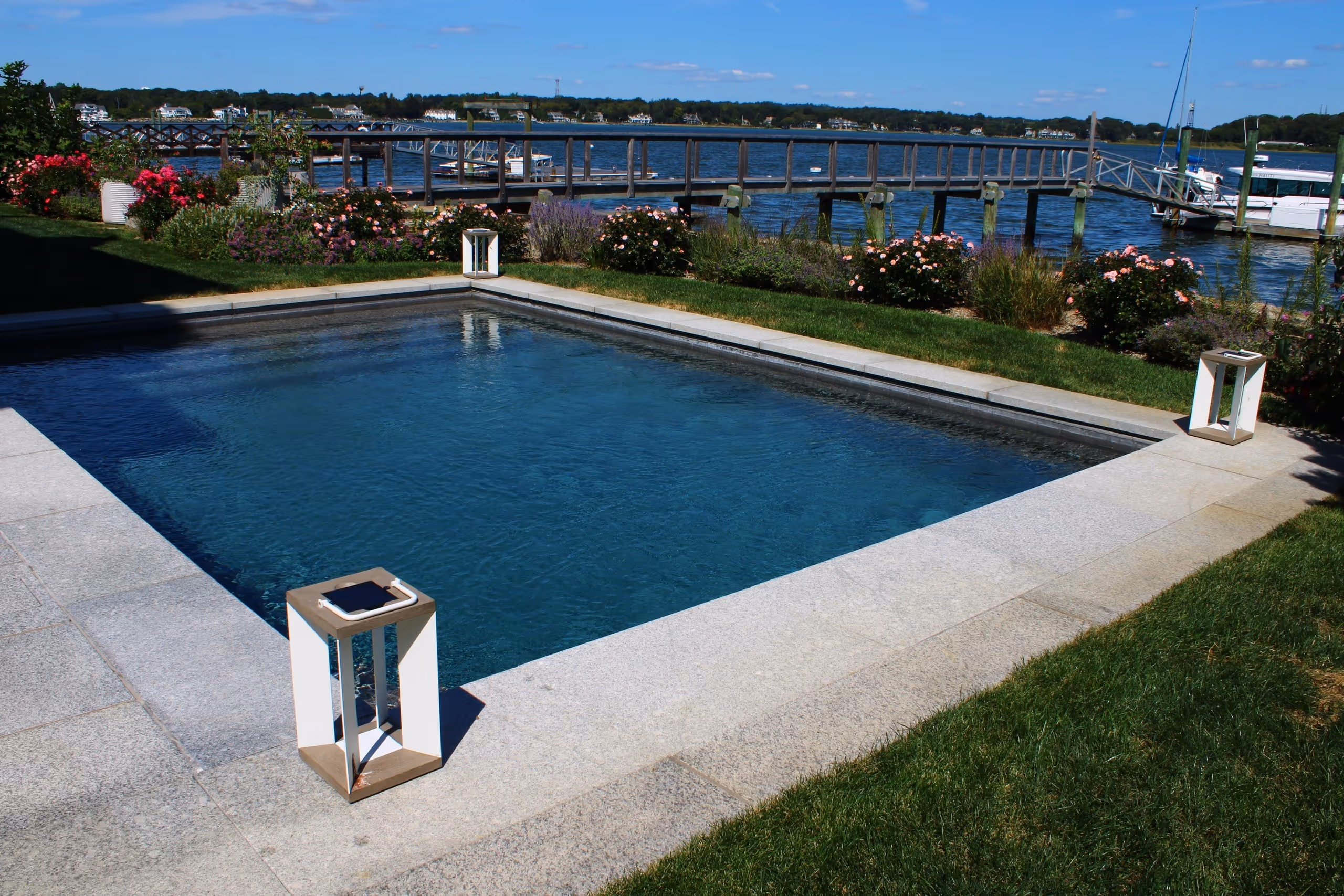 Elegant waterfront pool with stone deck and landscaped garden in New Canaan, CT by New Canaan Pool Service