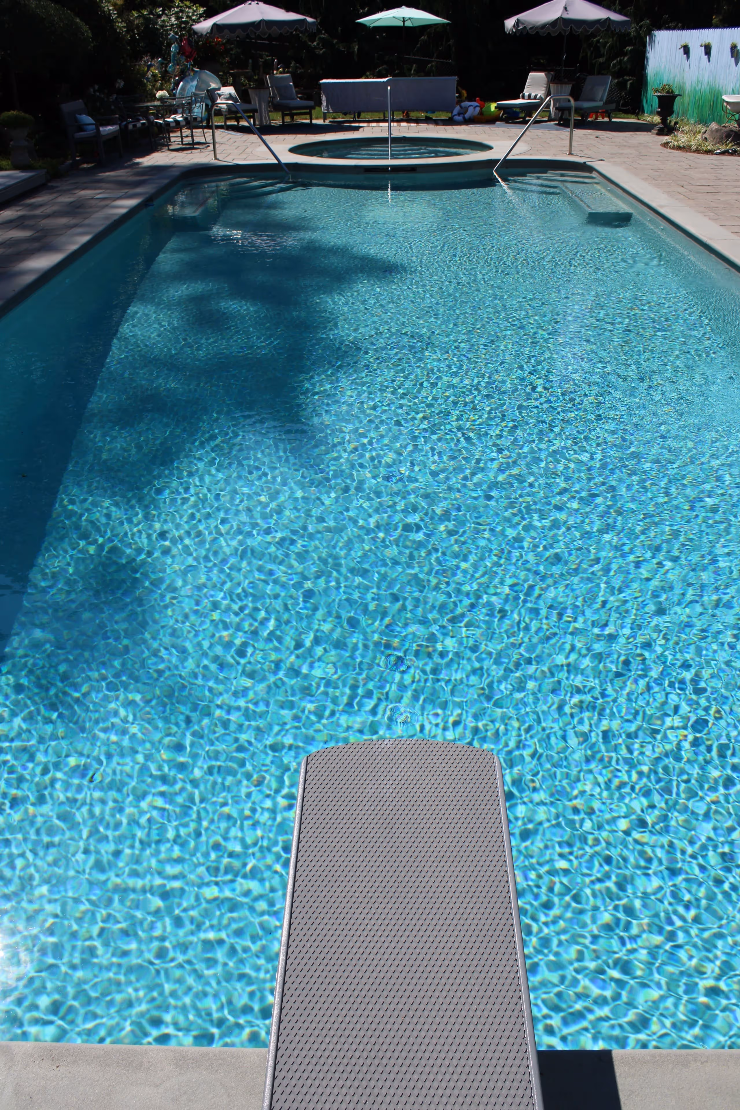 Inground swimming pool with diving board and attached spa in New Canaan, CT by New Canaan Pool Service