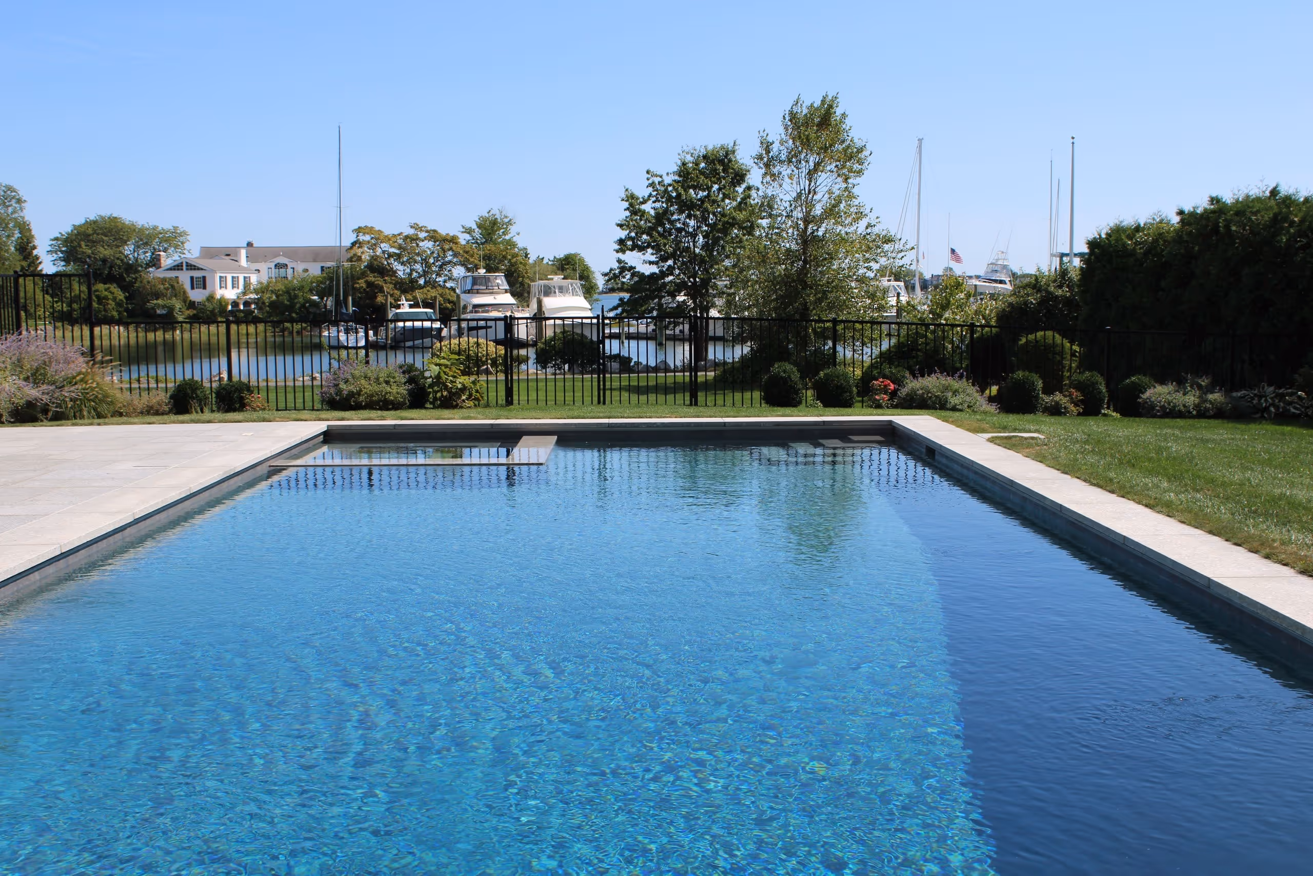 Custom waterfront pool with clear blue water and marina view in New Canaan, CT by New Canaan Pool Service