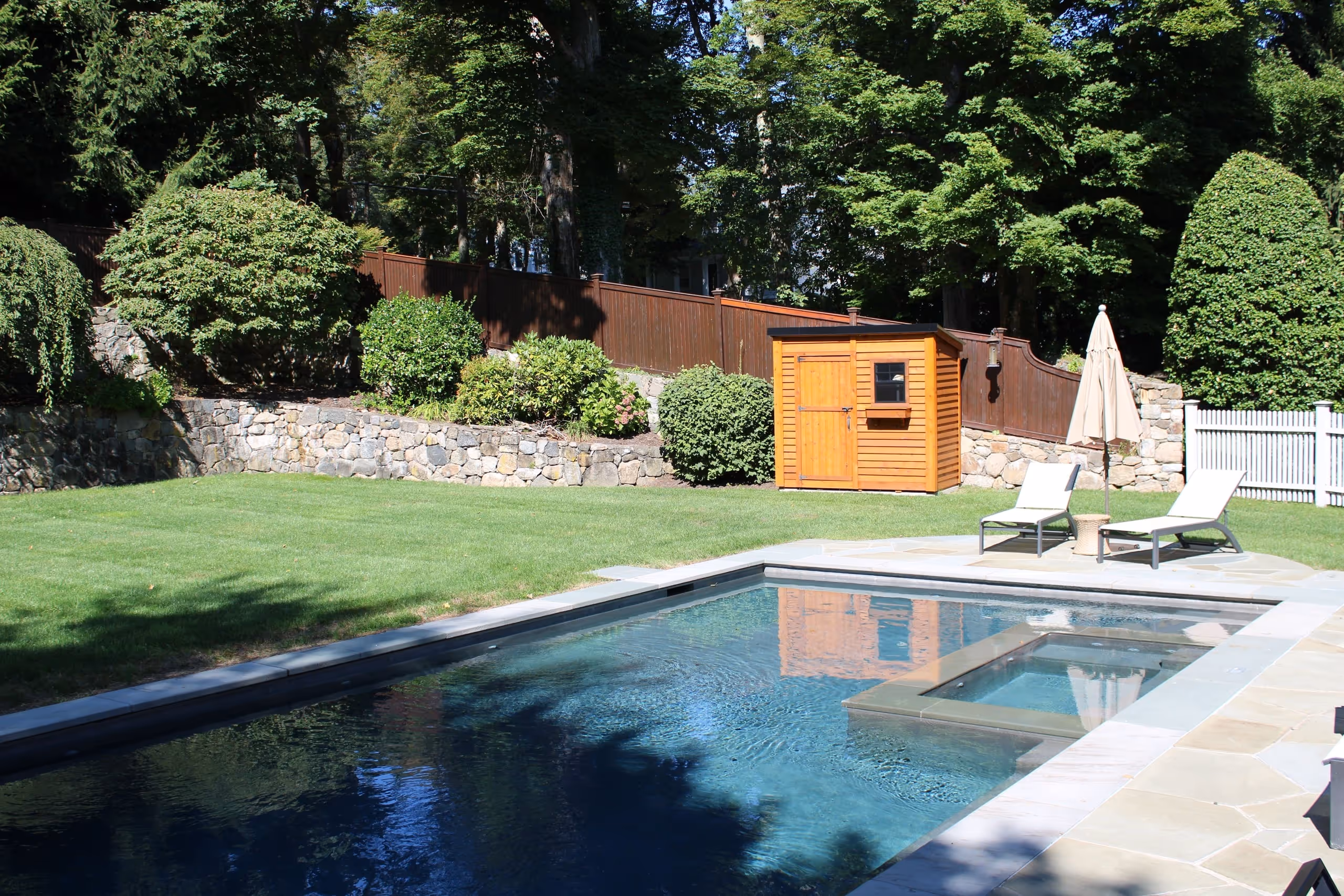 Custom inground pool with attached spa and landscaped backyard in New Canaan, CT by New Canaan Pool Service