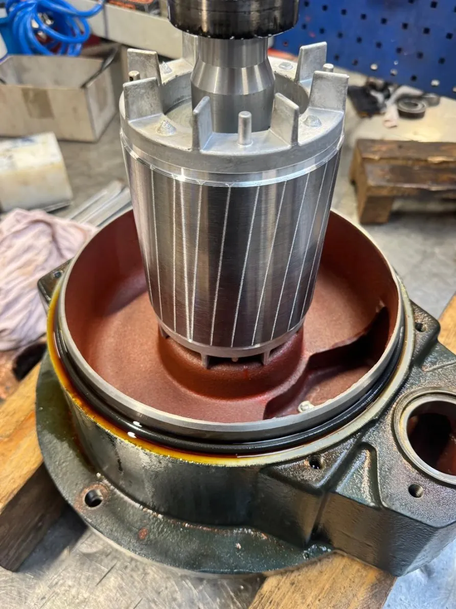 Close-up of a metallic rotor being assembled inside a motor housing on a workbench.