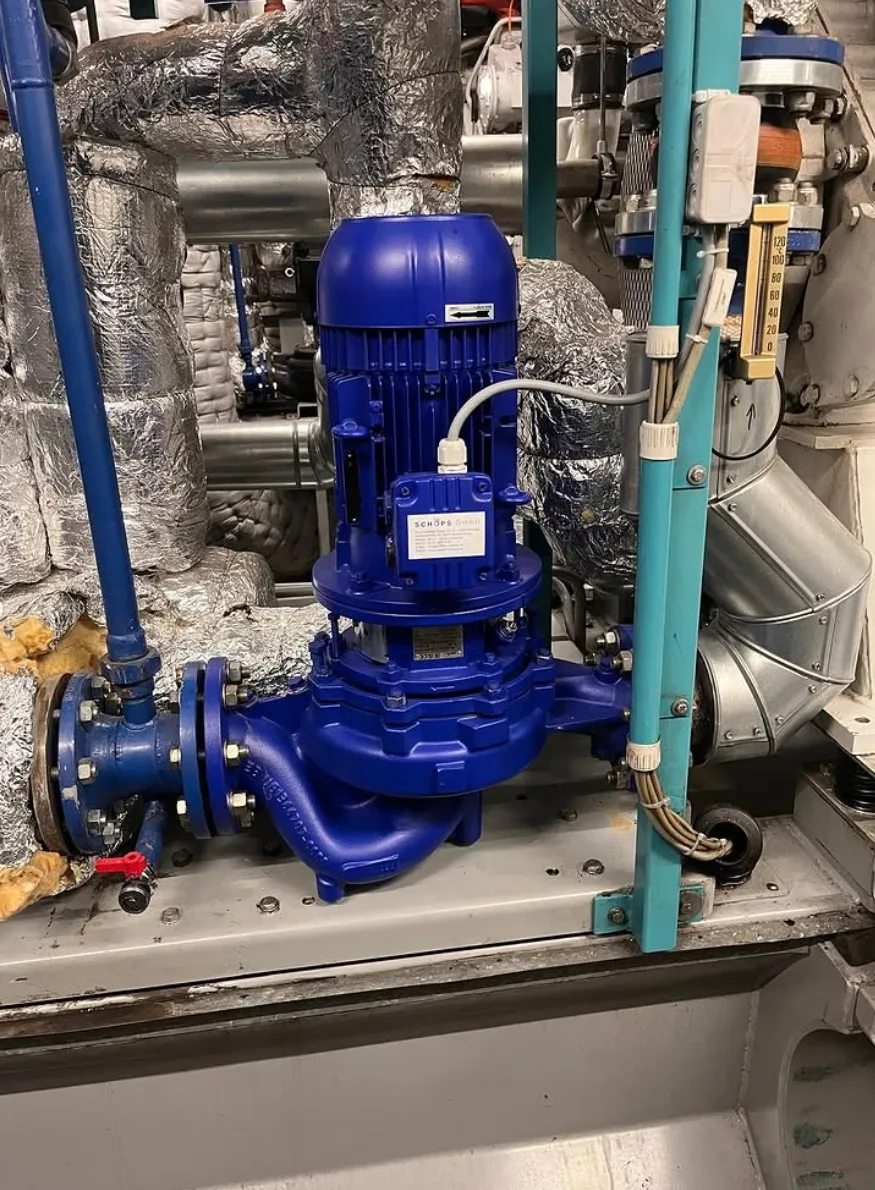 Blue industrial water pump installed on a metal base surrounded by insulated pipes and electrical wiring.