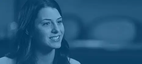 Smiling woman with dark hair looking slightly to the side against a blurred background.