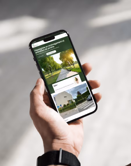 Main tenant un smartphone affichant un site de paysagisme et entretien de jardins.
