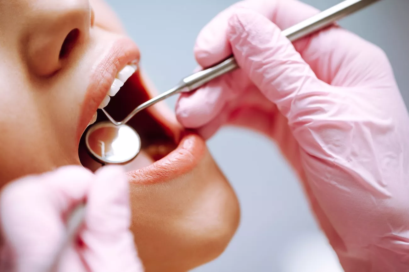 Dentist using a mirror and probe during a routine dental check-up to examine a patient's teeth
