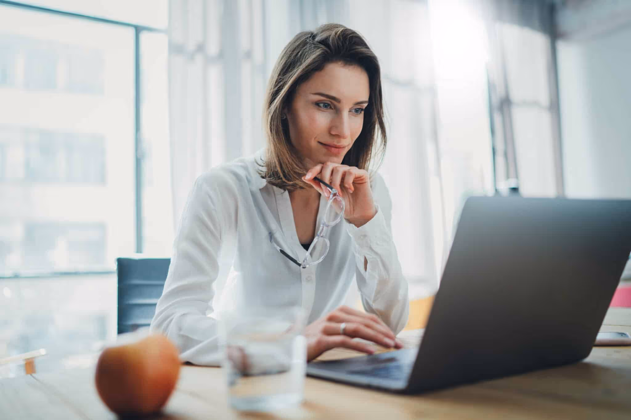 Confident businesswoman working on laptop at her workplace at modern office.Blurred background.