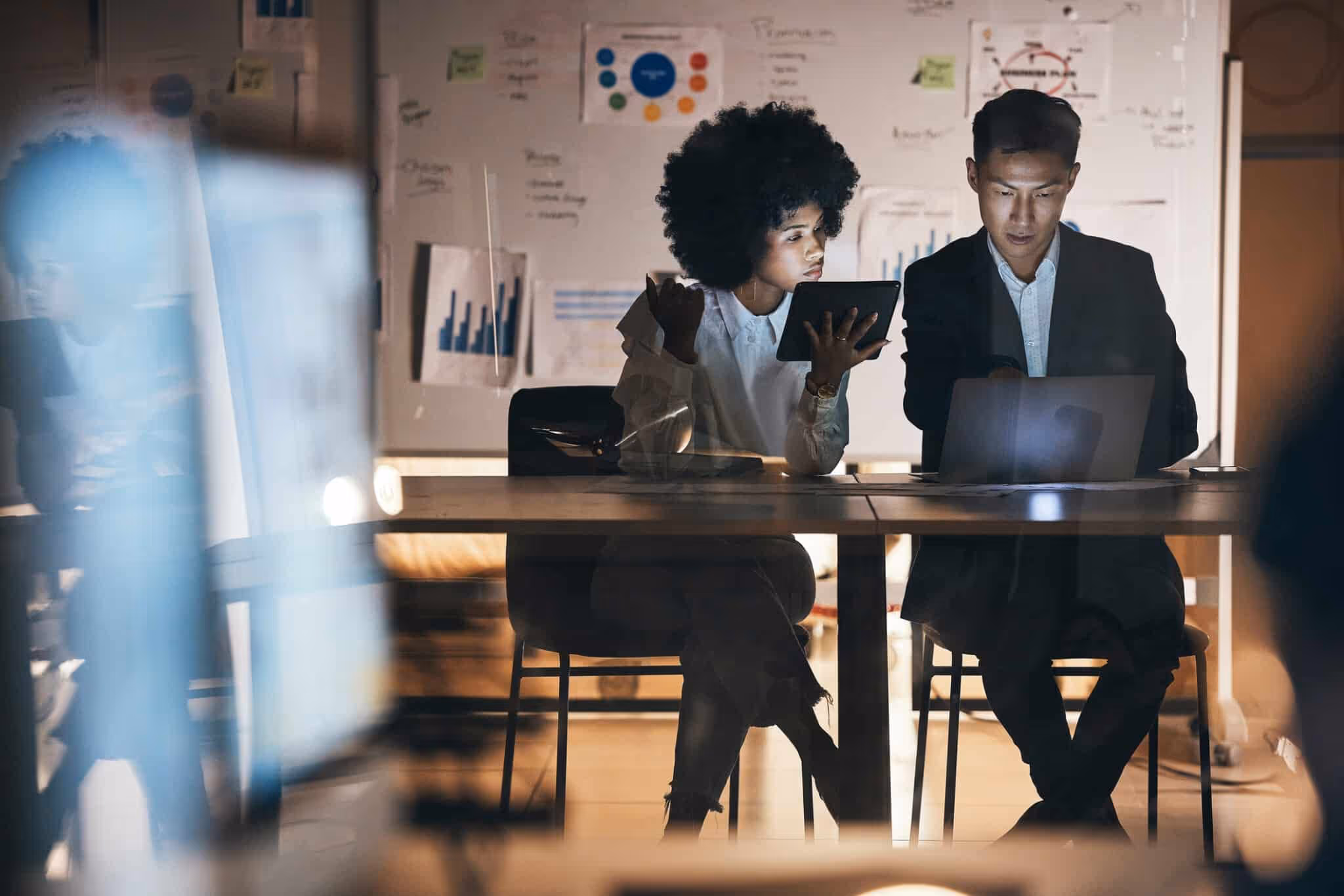 Working, night and office team with technology in the dark planning a IT and company code strategy. Diversity of teamwork collaboration on tablet ui, computer ux and website business with technology
