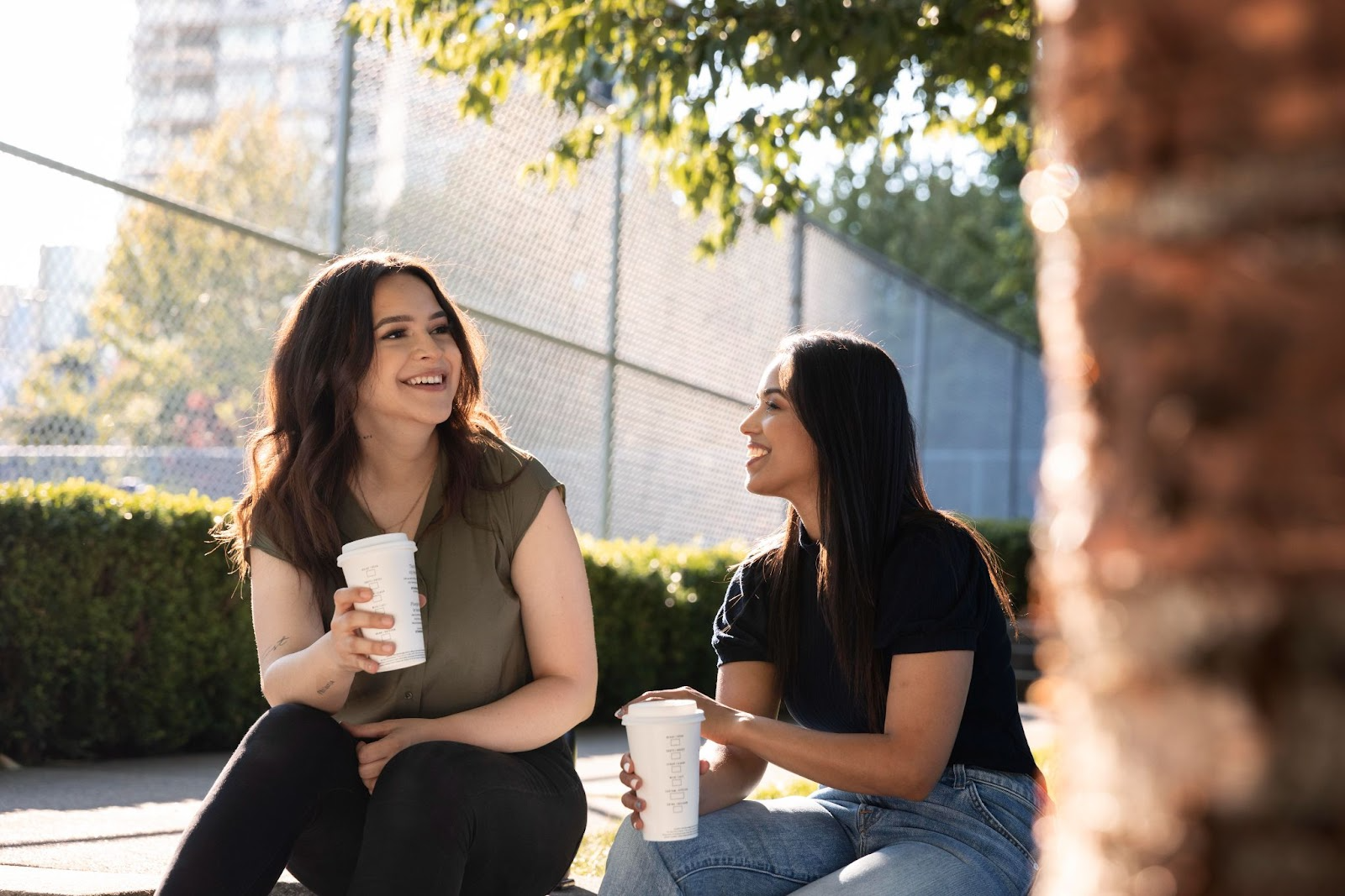 Two women sitting outside with coffee cups, enjoying conversation and friendship as part of recovery support during a 30-day program