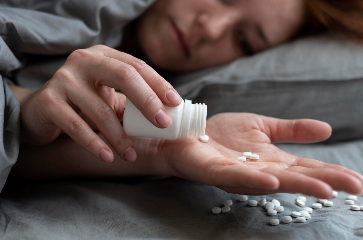 A closeup shot of a women lying in bed, trying to take pills