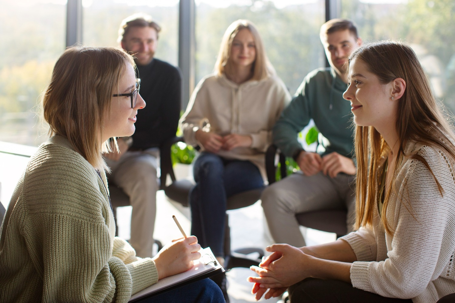 A person and a female therapist engaging in a group therapy session