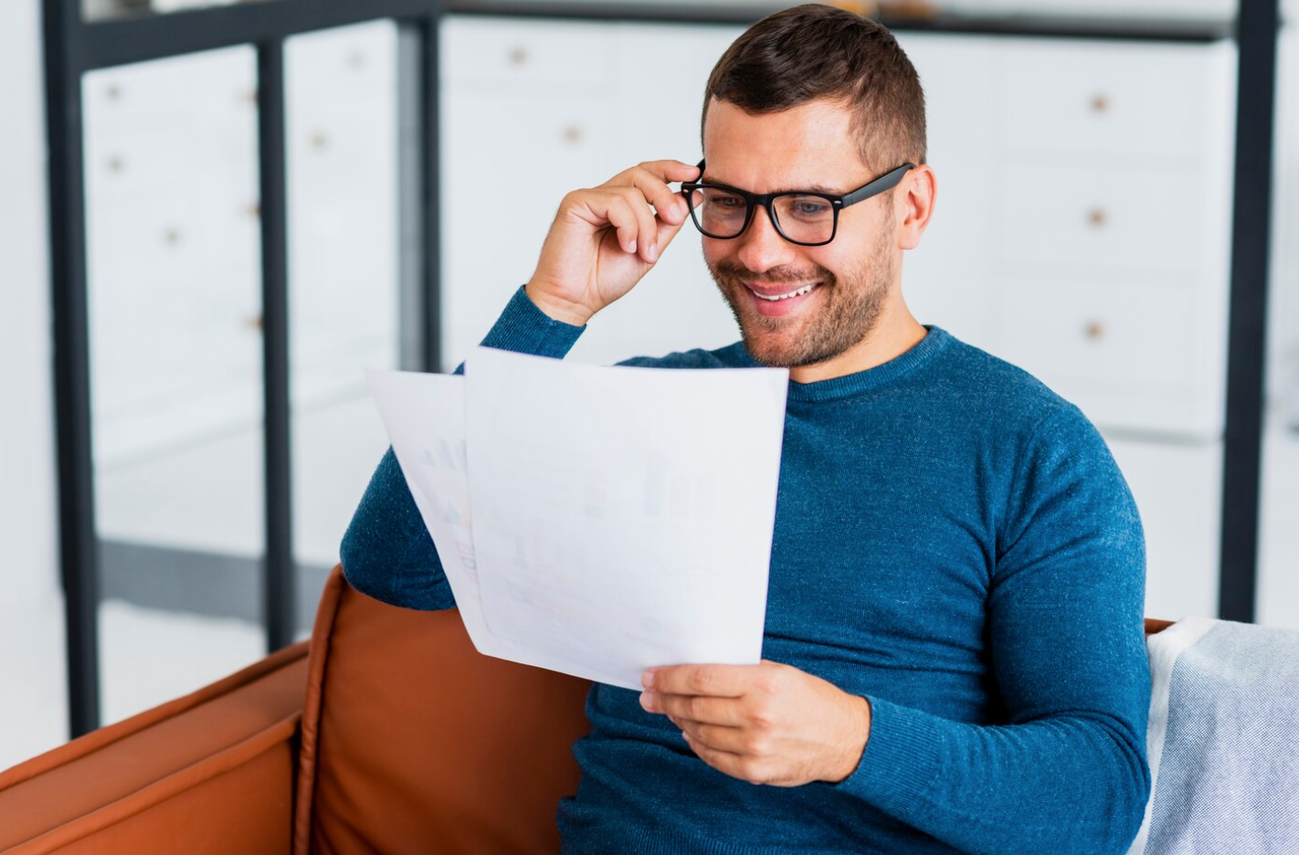 A smiling man with an eyeglass, holding and looking at a document of his new goals after completing a program in an addiction treatment center in South Carolina
