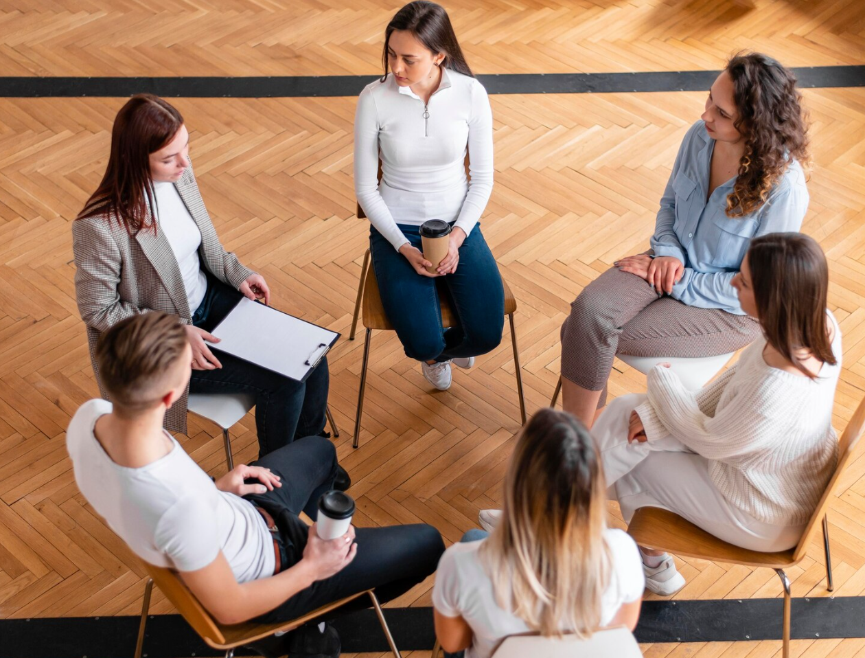 A diverse group of people engaged in peer counseling in an addiction treatment center