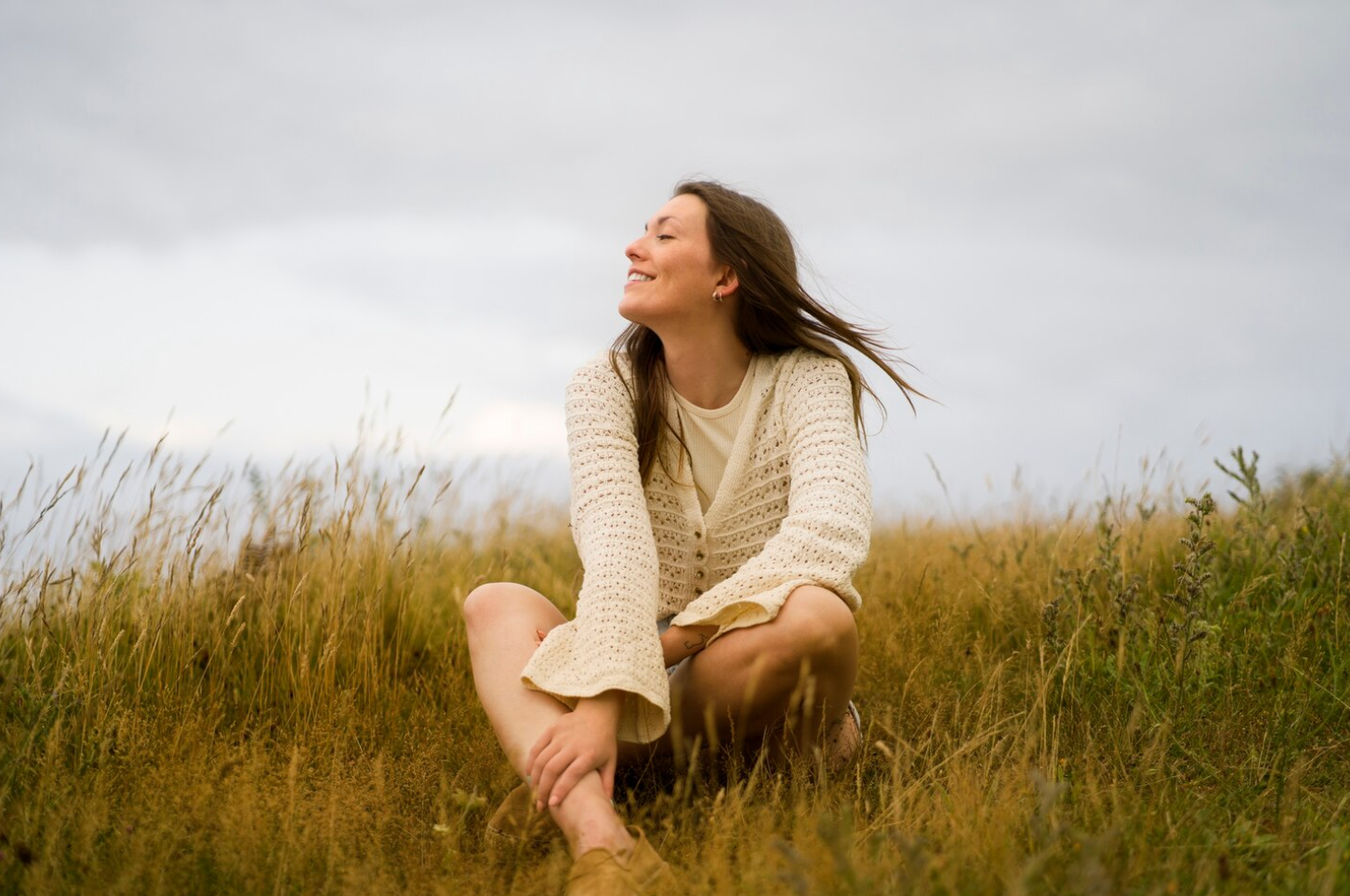 Woman sitting peacefully in a grassy field reflecting on recovery and personal growth during an intensive outpatient program