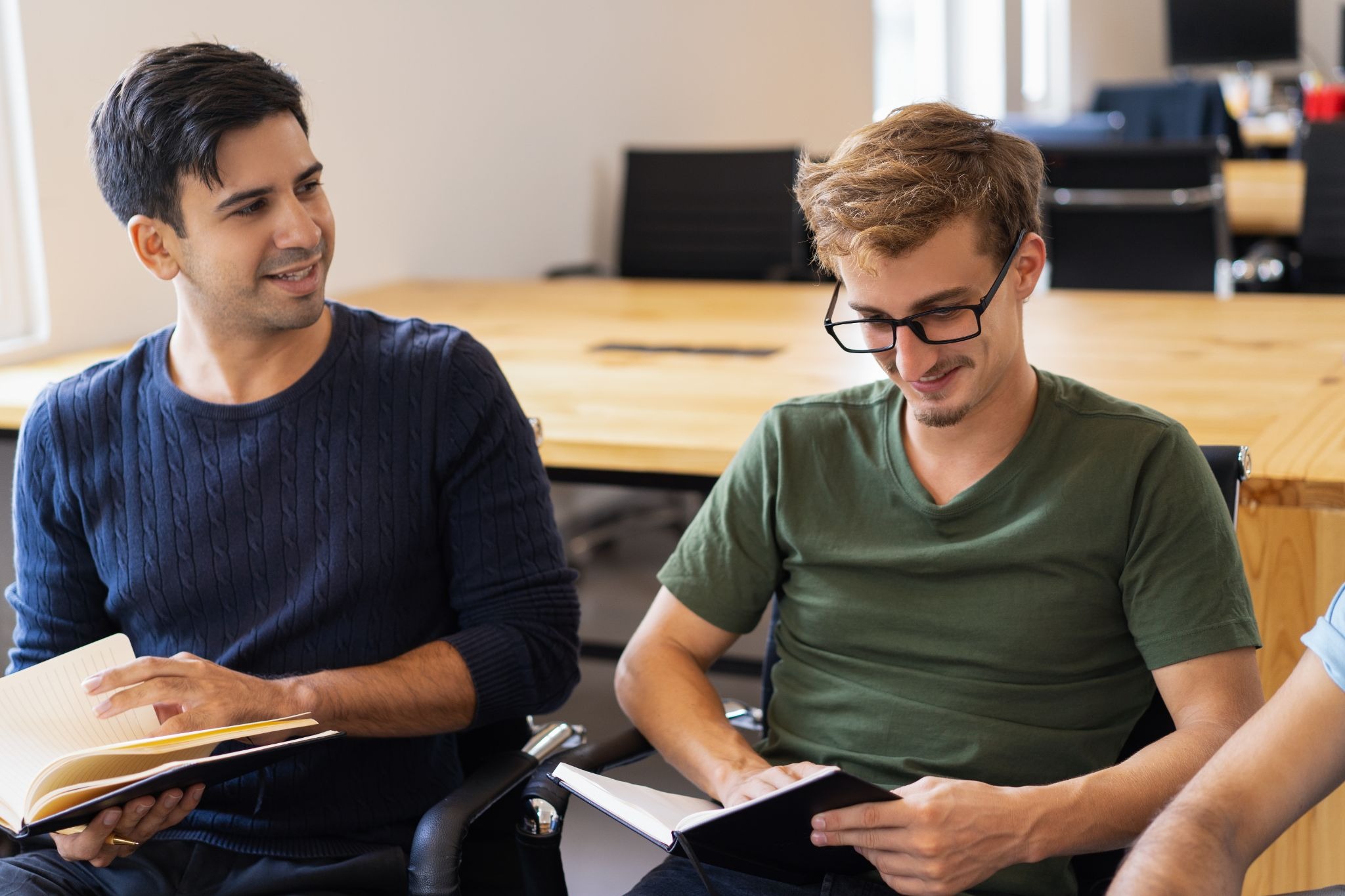 Two men participating in a peer support session while reading and discussing recovery materials together