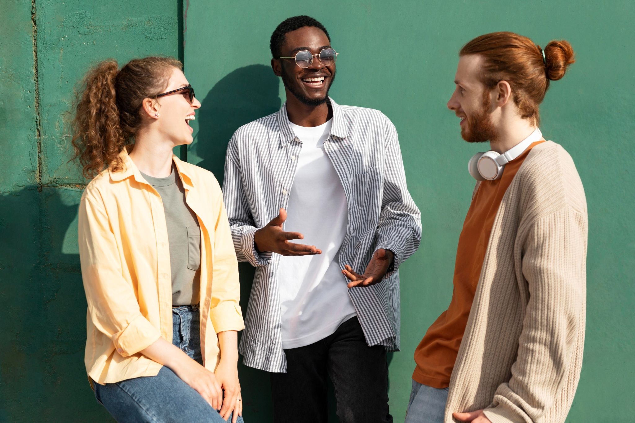 Three people talking and laughing outdoors, representing peer connection, shared encouragement, and the supportive relationships that strengthen recovery