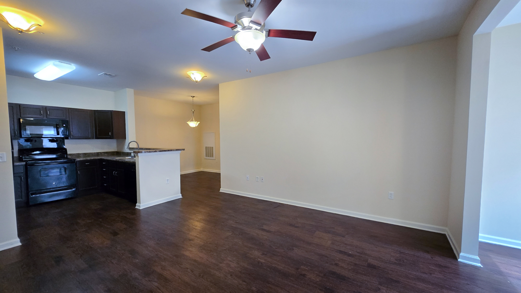 View of unfurnished livnig area and Kitchen with dark brown cabinets and black appliances