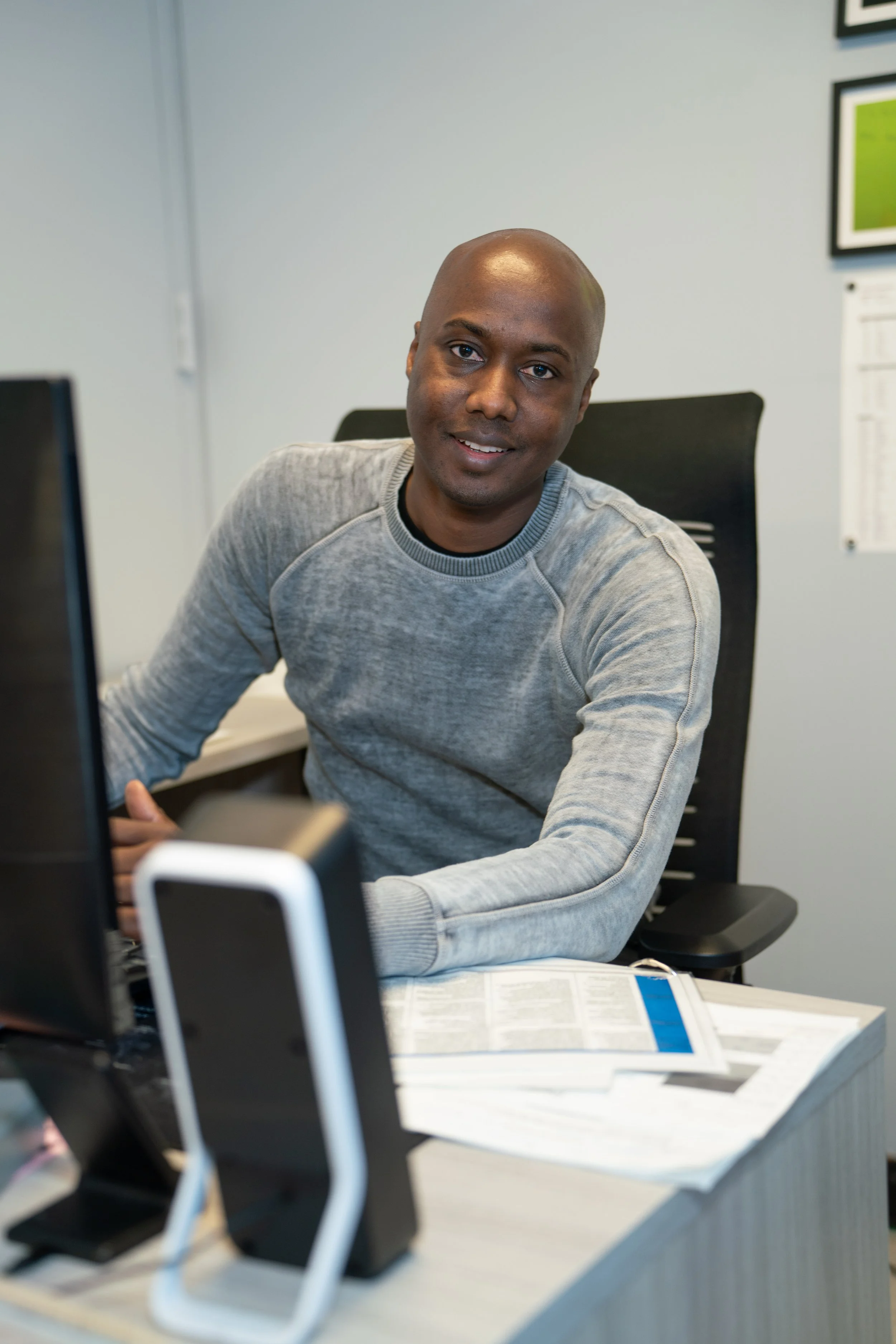 Staff member Henry smiling at his office desk with computer