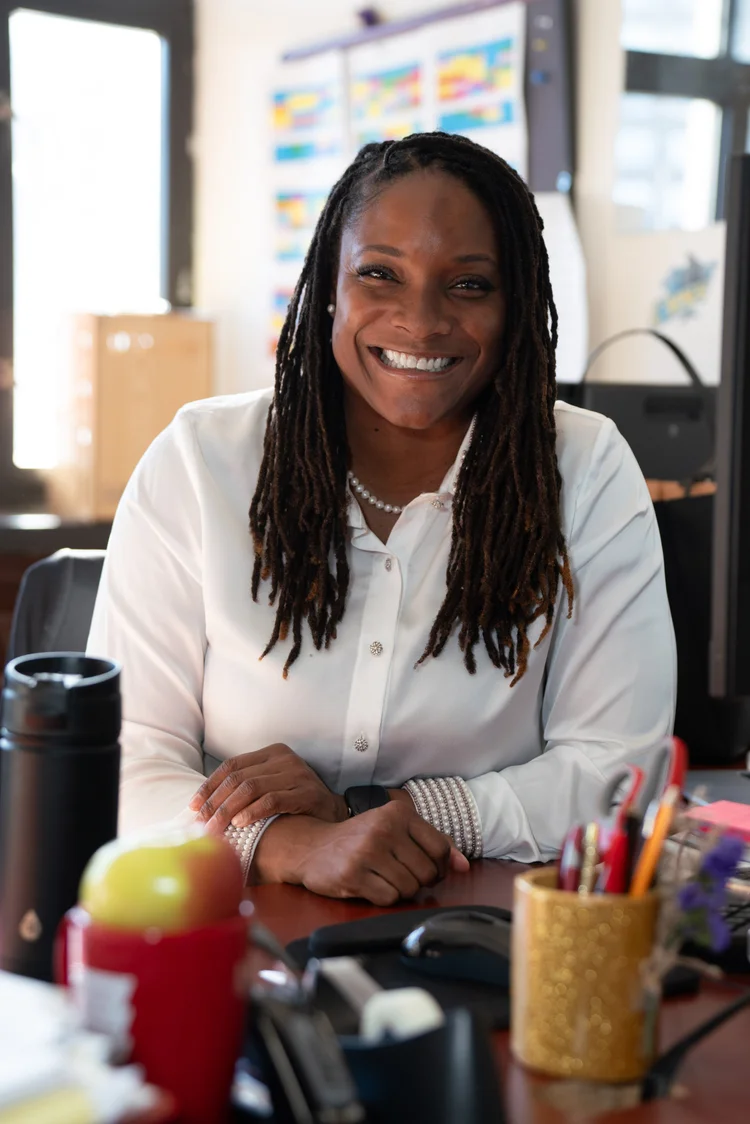 Staff member smiling at desk in school classroom office