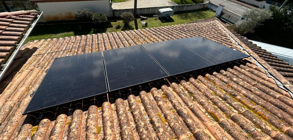 Installation de panneaux photovoltaïques sur une toiture en tuiles anciennes, exposée en plein soleil dans une zone résidentielle.